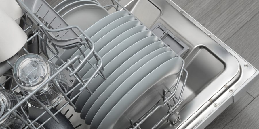 Opened domestic dishwasher with cleaned dishware in kitchen interior